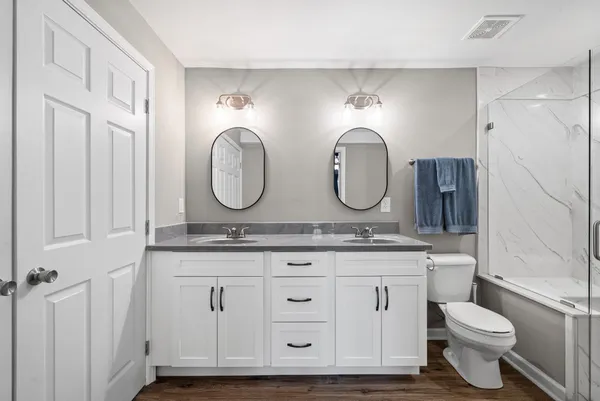 a bathroom with a granite countertop toilet a sink and a mirror