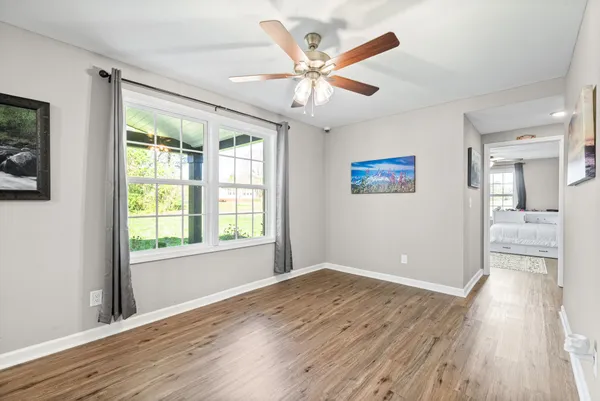 a view of an empty room with wooden floor and a window