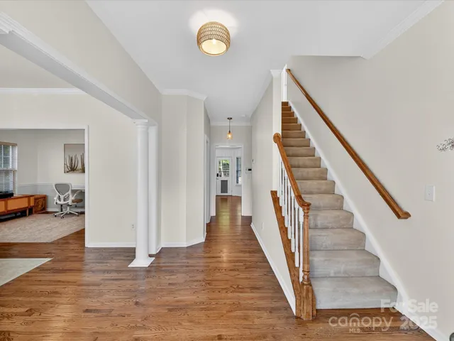 a view of a hallway with wooden floor and stairs