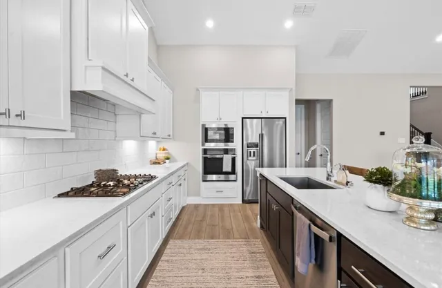 a large kitchen with stainless steel appliances granite countertop a lot of counter space and wooden floor