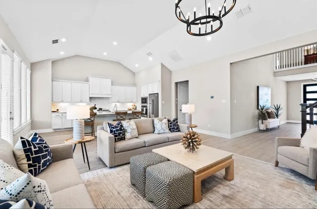 a living room with furniture kitchen view and wood floor