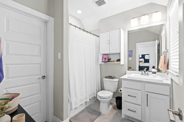a bathroom with a toilet sink vanity tub and mirror