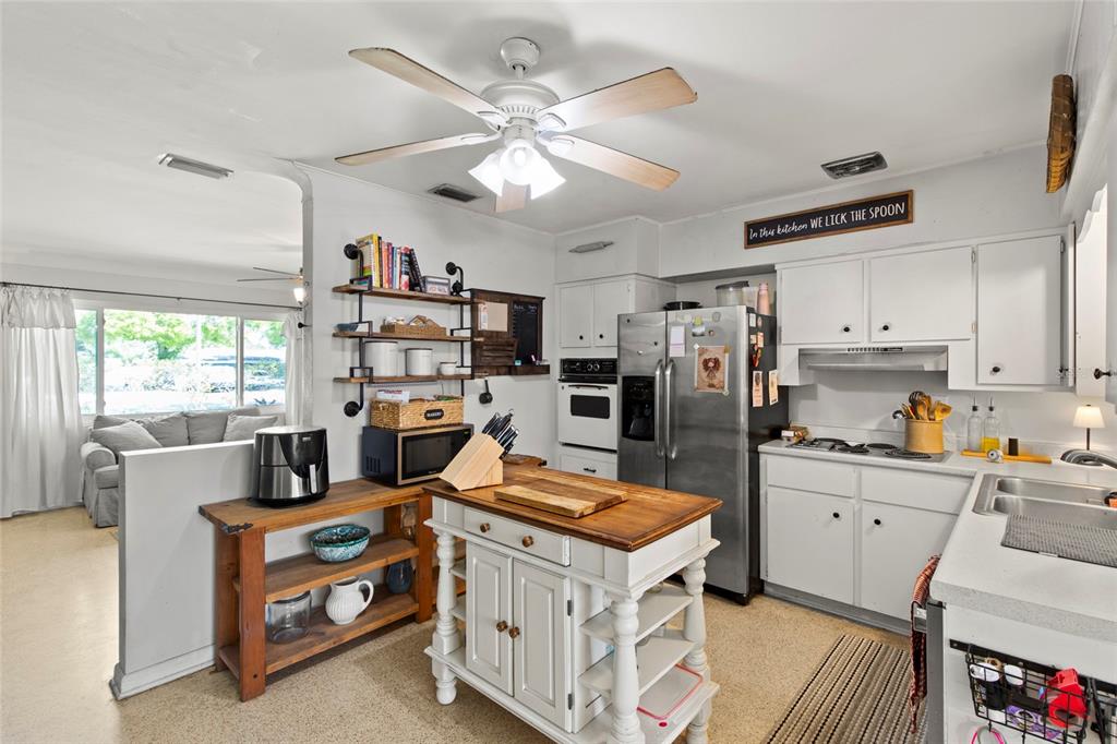 1361 Belleair Road Clearwater, FL 33756 - Photo 3 of 19 a kitchen with stainless steel appliances a stove a refrigerator a sink a stove and white cabinets with wooden floor