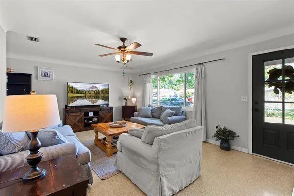 a living room with furniture a ceiling fan a flat screen tv and a window
