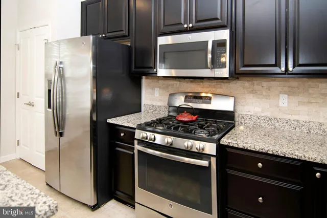 a kitchen with stainless steel appliances granite countertop a stove microwave and refrigerator
