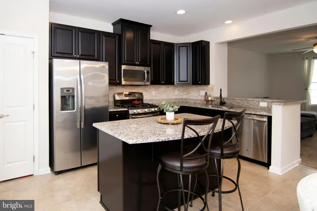 a kitchen with stainless steel appliances kitchen island a table chairs refrigerator and a sink