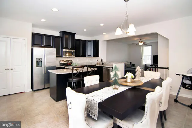 a kitchen with stainless steel appliances kitchen island granite countertop a dining table chairs refrigerator and microwave