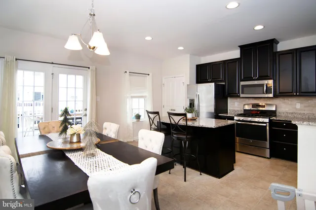 a living room with stainless steel appliances kitchen island granite countertop a stove a sink a dining table and chairs