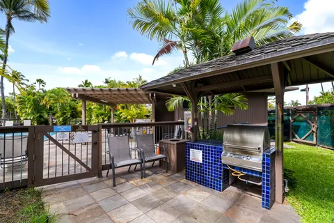 a view of a patio with table and chairs under an umbrella with a small yard