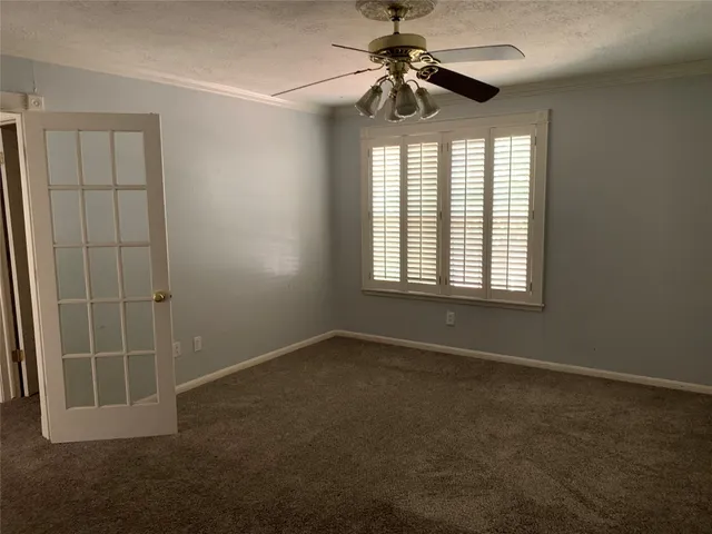 an empty room with windows and fan