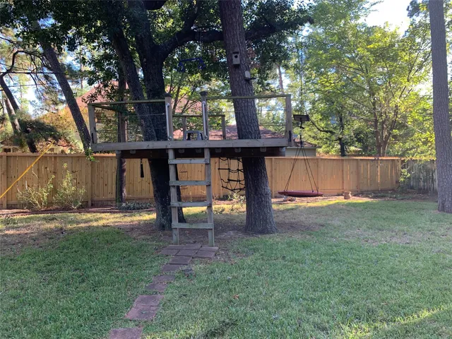 a view of a backyard with large trees and wooden fence