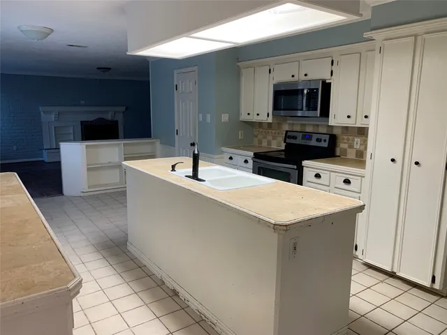 a kitchen with stainless steel appliances a sink a stove a microwave a sink a refrigerator and cabinets