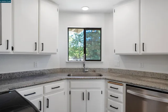 a kitchen with granite countertop white cabinets and a window