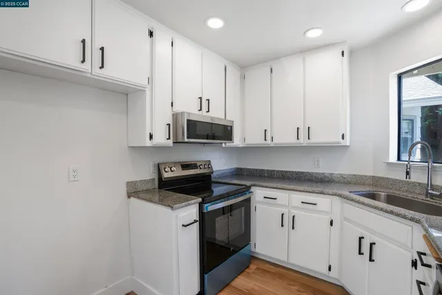 a kitchen with stainless steel appliances granite countertop white cabinets stove a sink and dishwasher