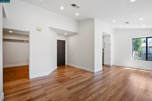 an empty room with wooden floor and windows