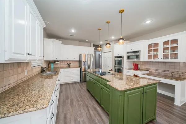 a kitchen with a stove a sink dishwasher a kitchen island with wooden cabinets and floor
