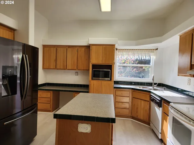 a kitchen with granite countertop stainless steel appliances a refrigerator stove top oven and sink