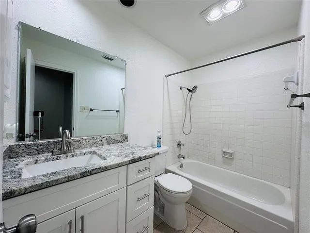 a bathroom with a granite countertop sink a toilet and shower