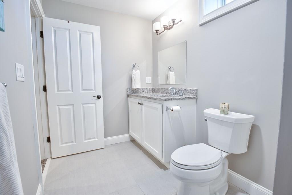 185 Cross Street Winchester, MA 01890 - Photo 33 of 41 a bathroom with a granite countertop toilet a sink and a mirror