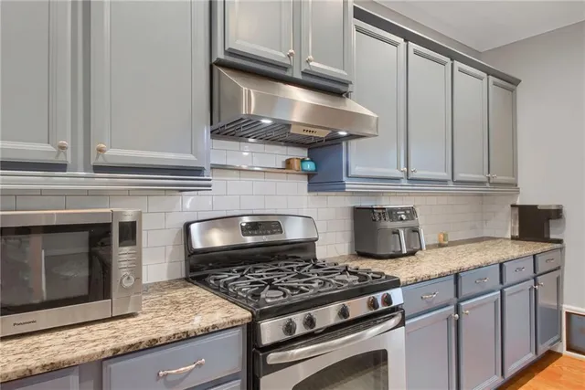 a kitchen with granite countertop a stove and a white cabinets