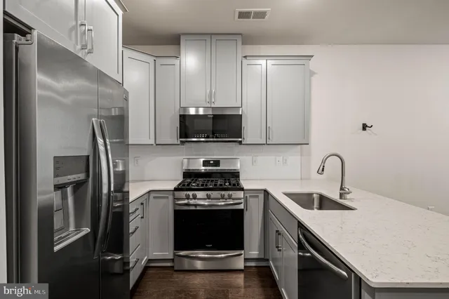 a kitchen with stainless steel appliances a refrigerator a sink a stove and cabinets