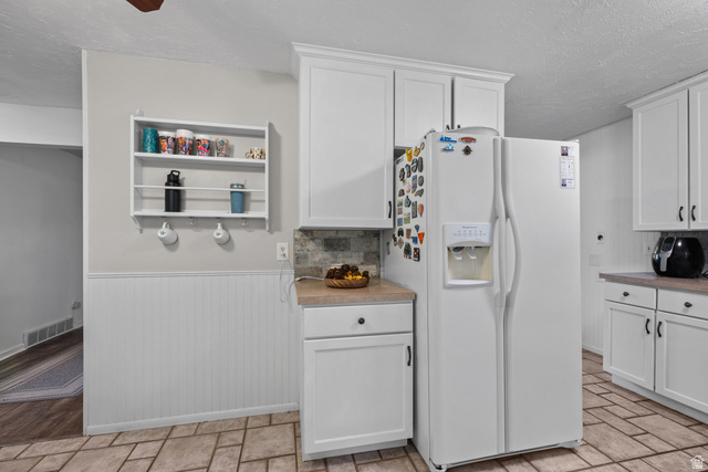 7659 State Street Midvale, UT 84047 - Photo 11 of 33 White cabinetry with matte black hardware, stone-finish countertops, tiled backsplash, and patterned floor tiling