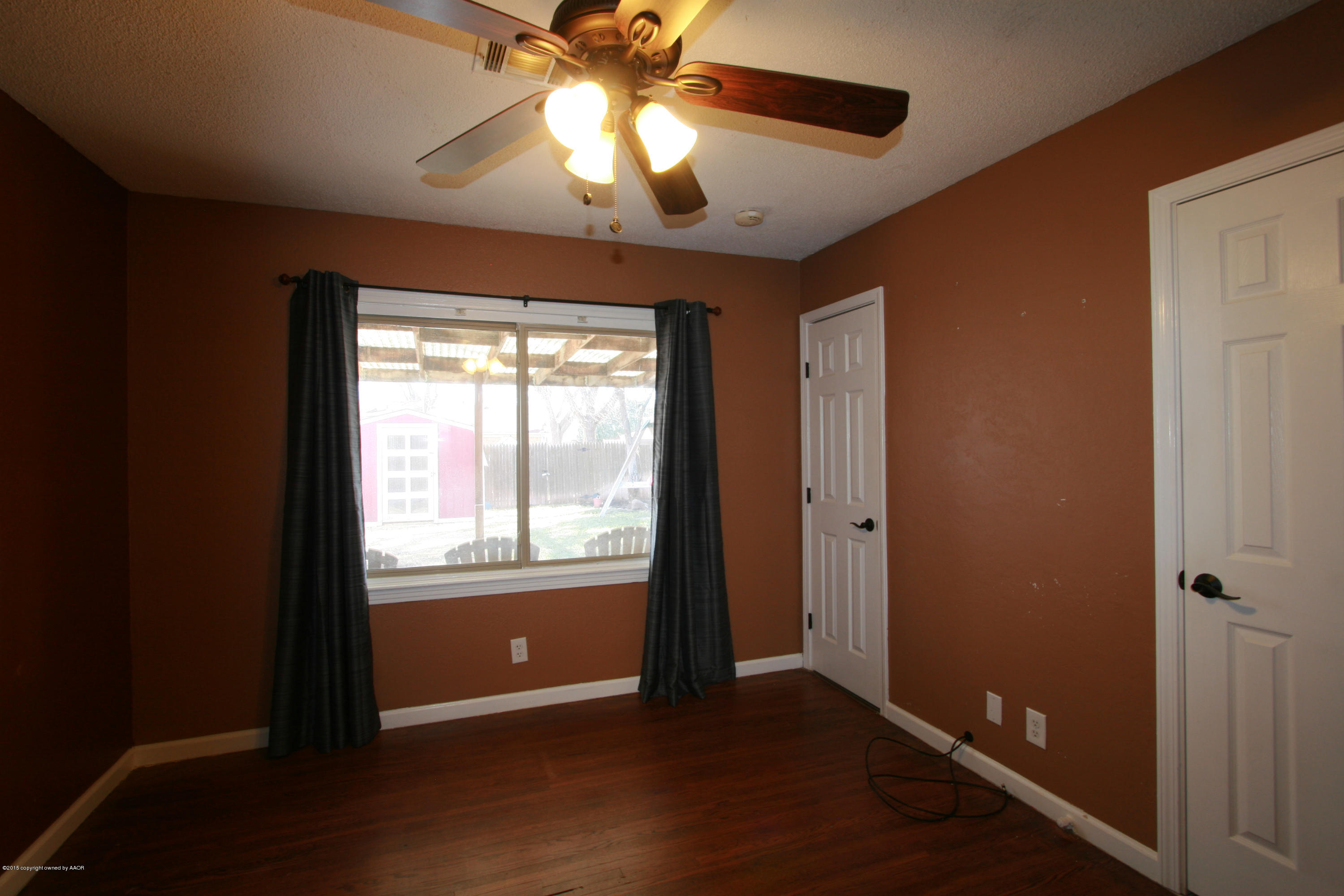 1011 South Rusk Street Amarillo, TX 79102 - Photo 7 of 11 an empty room with wooden floor chandelier fan and windows