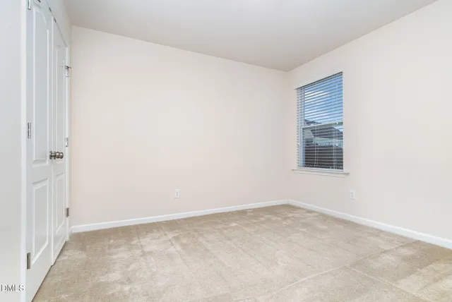 an empty room with chandelier fan and windows