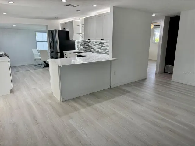 a view of kitchen with stainless steel appliances kitchen island wooden floors and living room view