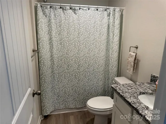 a bathroom with a granite countertop toilet and a sink