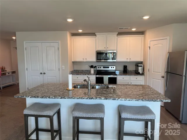 a kitchen with stainless steel appliances granite countertop a stove refrigerator sink and cabinets