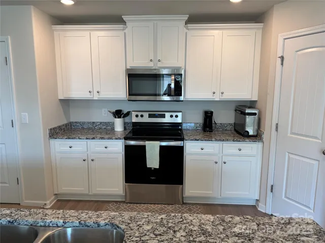 a kitchen with stainless steel appliances granite countertop a stove a microwave and cabinets