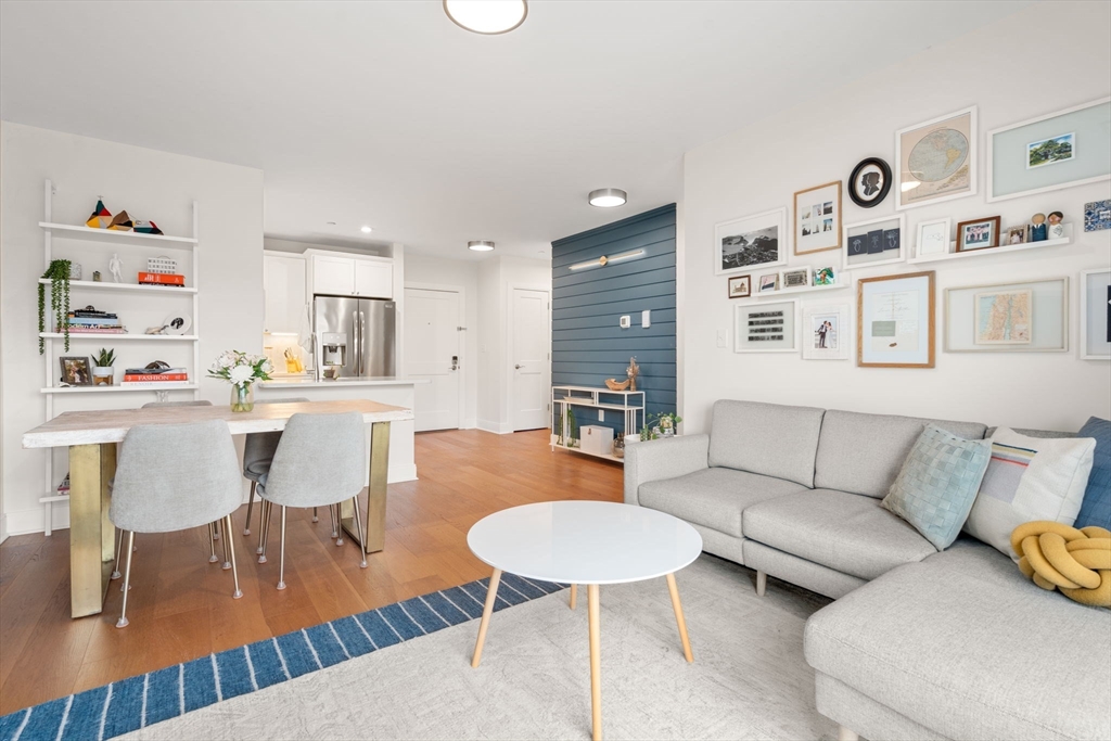 a living room with furniture and a dining table with wooden floor