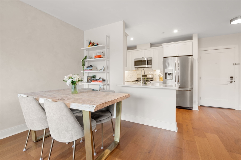 3 Bennett Street, Unit 402 Wakefield, MA 01880 - Photo 2 of 23 a kitchen with stainless steel appliances kitchen island granite countertop a refrigerator a stove top oven and a dining table with wooden floor