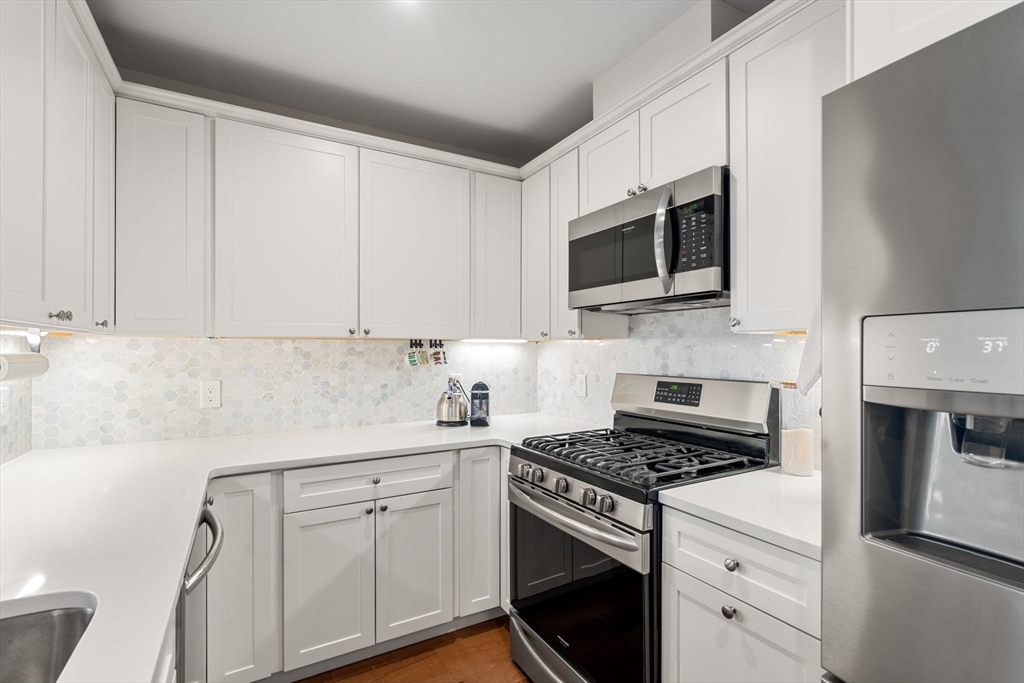 3 Bennett Street, Unit 402 Wakefield, MA 01880 - Photo 4 of 23 a kitchen with white cabinets and white appliances
