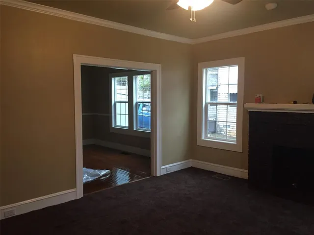 a view of an empty room with a window and wooden floor