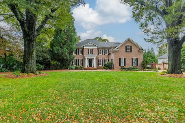 a view of a house with a big yard and large trees