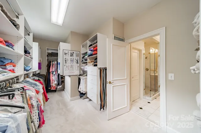 a walk in closet with clothes and shoes