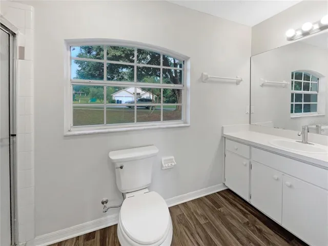 a bathroom with a toilet sink vanity and windows