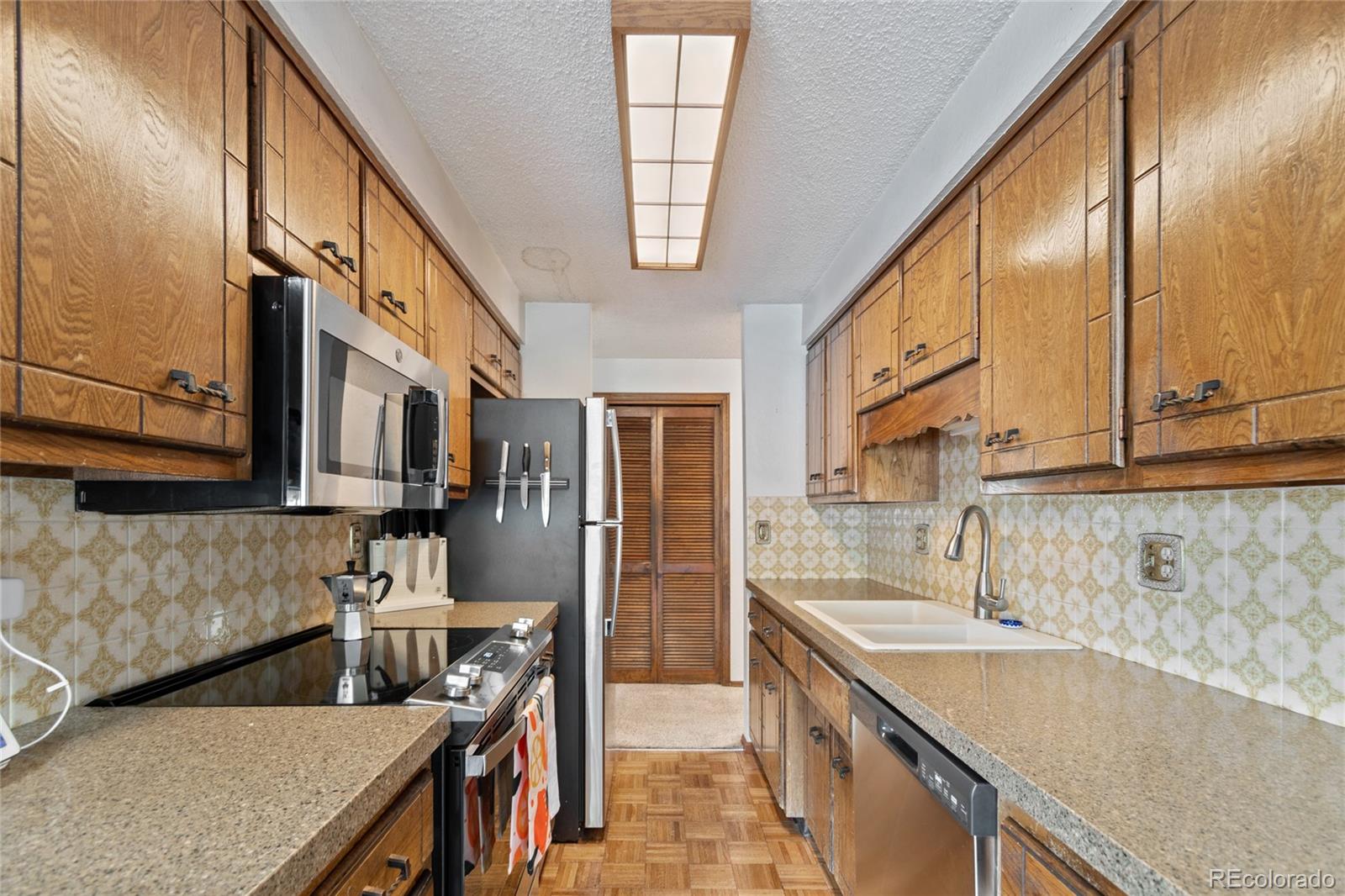 3315 Marshall Street Wheat Ridge, CO 80033 - Photo 10 of 30 a kitchen with stainless steel appliances granite countertop a sink a stove and a wooden floors
