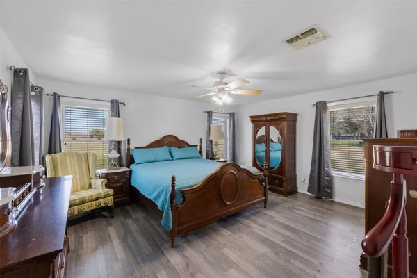 a bedroom with a bed wooden floor and lamp on desk