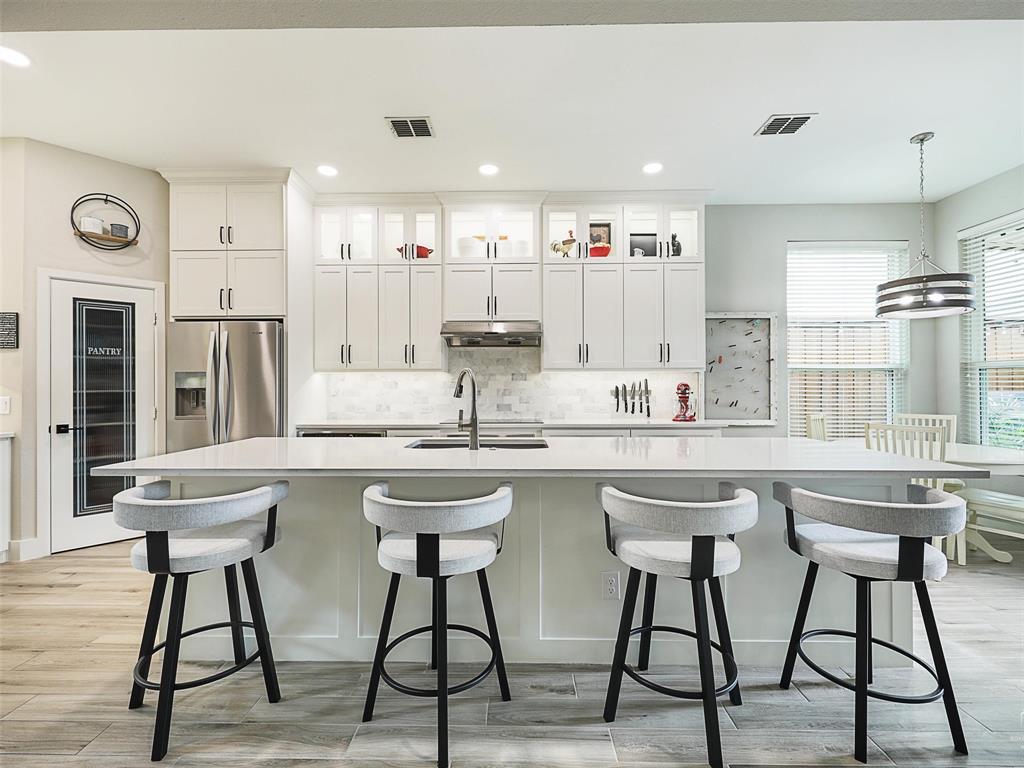 a kitchen with stainless steel appliances a white table chairs and a window