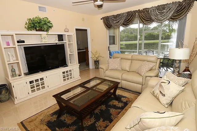 a living room with furniture a flat screen tv and a floor to ceiling window