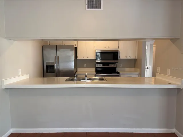 a large kitchen with stainless steel appliances a sink a stove and a refrigerator