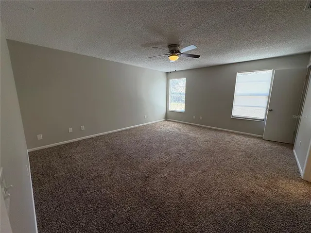an empty room with windows and fan
