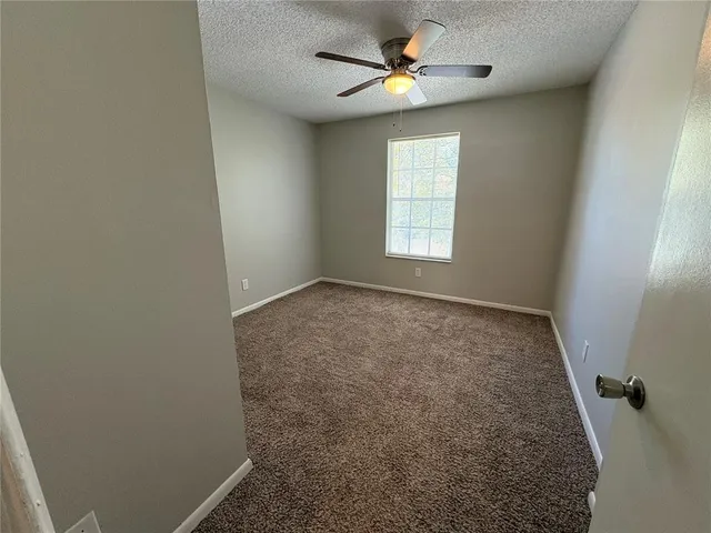 en empty room with windows and ceiling fan