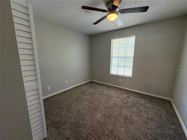an empty room with ceiling fan and window