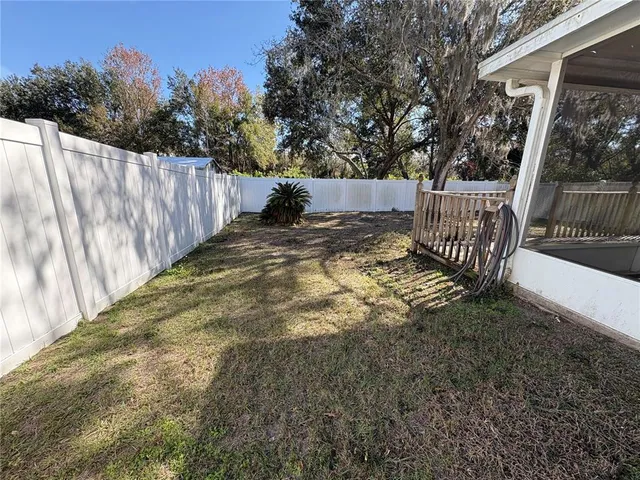 a view of backyard with wooden fence and trees