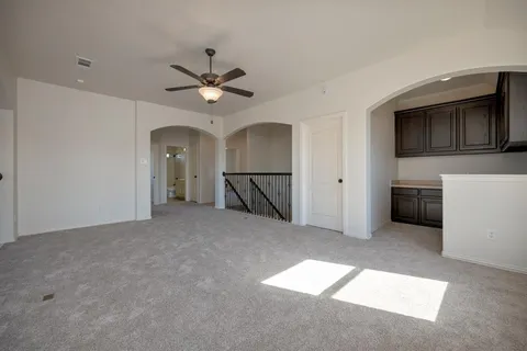 a view of a livingroom with a ceiling fan a kitchen space a ceiling fan and windows