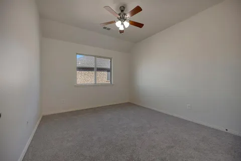 a view of an empty room and chandelier fan